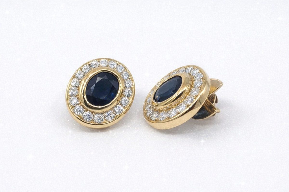Pair of luxurious 18k yellow gold stud earrings featuring deep blue oval sapphires of 4.0ct totaling encircled by a halo of 32 sparkling round-cut diamonds of 1.28ct.