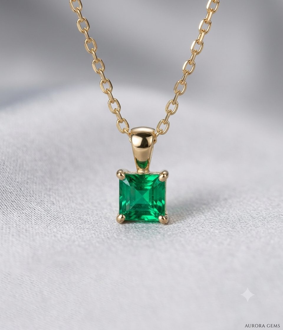 Vibrant green square princess-cut emerald pendant featuring a polished yellow gold bail and four-prong mounting, displayed on a fine gold chain in 9ct.