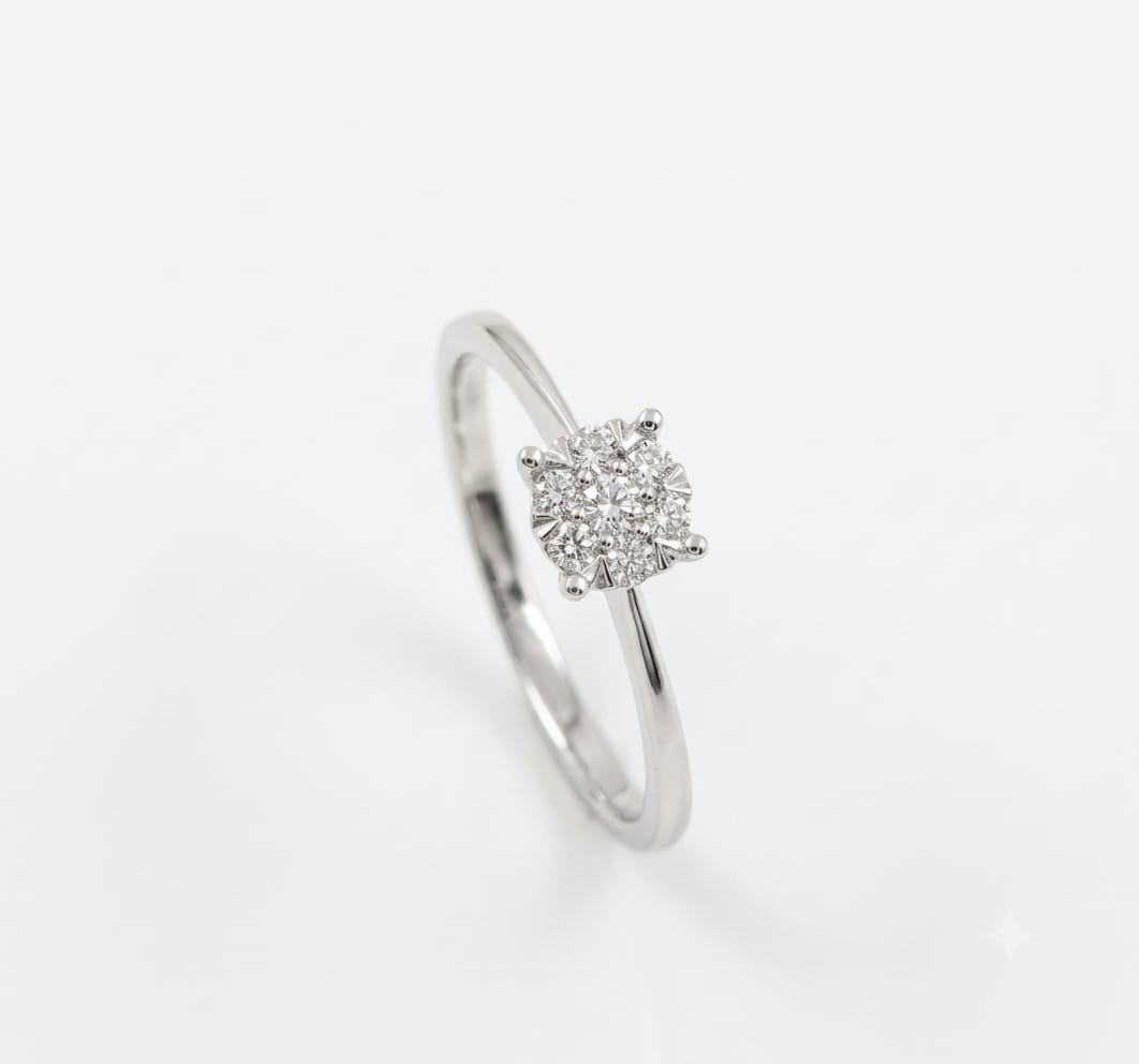 A 9ct white gold cluster ring. It features an array of brilliant round-cut diamonds at the center, set closely together to resemble a larger, square-shaped diamonds. The cluster is secured by a neat, four-claw setting on a delicate, plain gold shank.