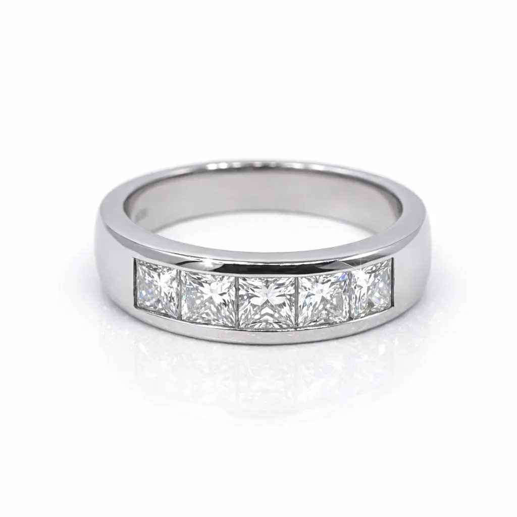 Jc pic Barbara Platinum diamond rin Platinum channel‑set ring featuring five princess‑cut diamonds arranged in a seamless row, photographed against a pure white background. The polished platinum band reflects soft light, while each diamond catches a crisp sparkle, showcasing precision craftsmanship and modern elegance.