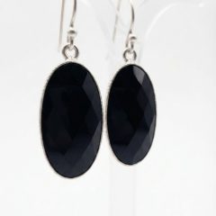 A pair of silver oval earrings with black checkerboard-cut onyx stones on Sheppard hooks.