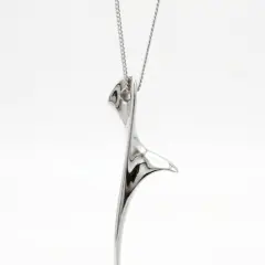 A sleek, abstract silver pendant titled "The Dancer" suspended on a delicate silver chain 44cm long.