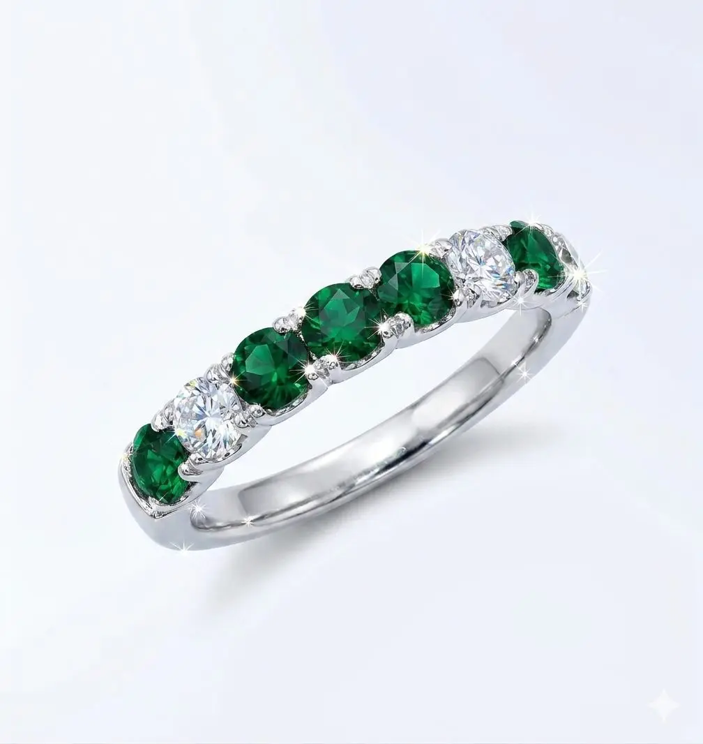 1777723043402 A detailed product of a white gold eternity band set with round green Tourmalines and wound diamonds. The stones are arranged in an alternating pattern with larger 3 Tourmalines in the center.