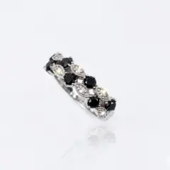 A 9ct. White Gold ring featuring a distinctive marquise and round-cut pattern. The band showcases alternation section: marquise-shaped settings pave-set with small brilliant white diamonds what emit bright, star-shaped sparkles, and round black diamonds secured by delicate prongs (claws).