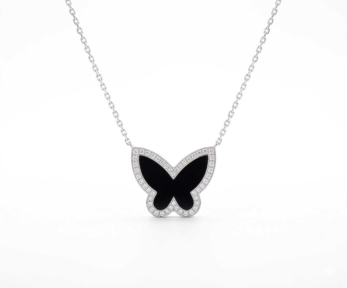 1777722200834 A high-quality 18ct. White gold butterfly pendant necklace featuring a striking black onyx inlay wing design. The butterfly is bordered by a delicate row of shimmering pave-set diamonds an suspended from a polished 18ct. White Gold Anchor chain.