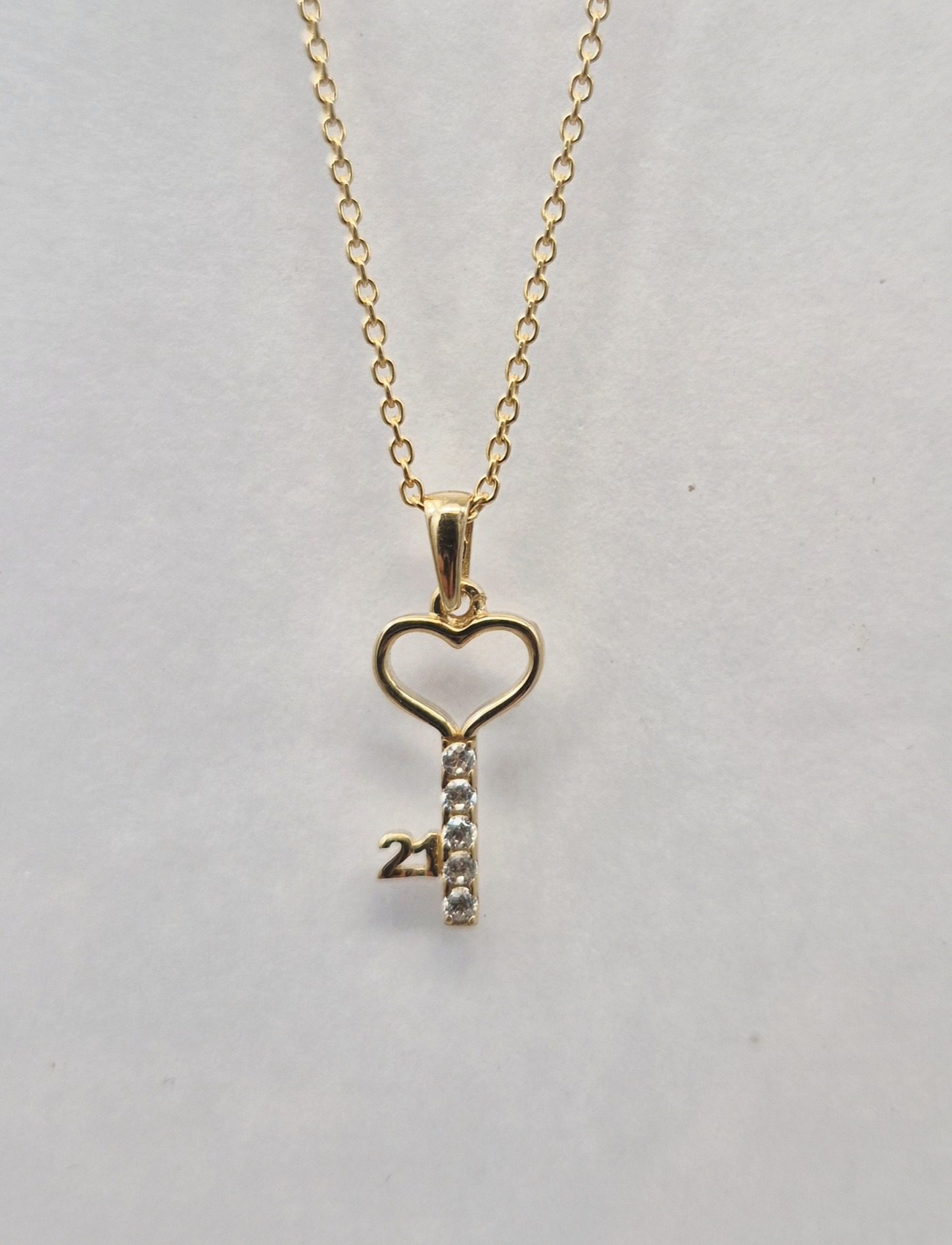 A delicate gold neck chain with a small, circular diamond pendant.