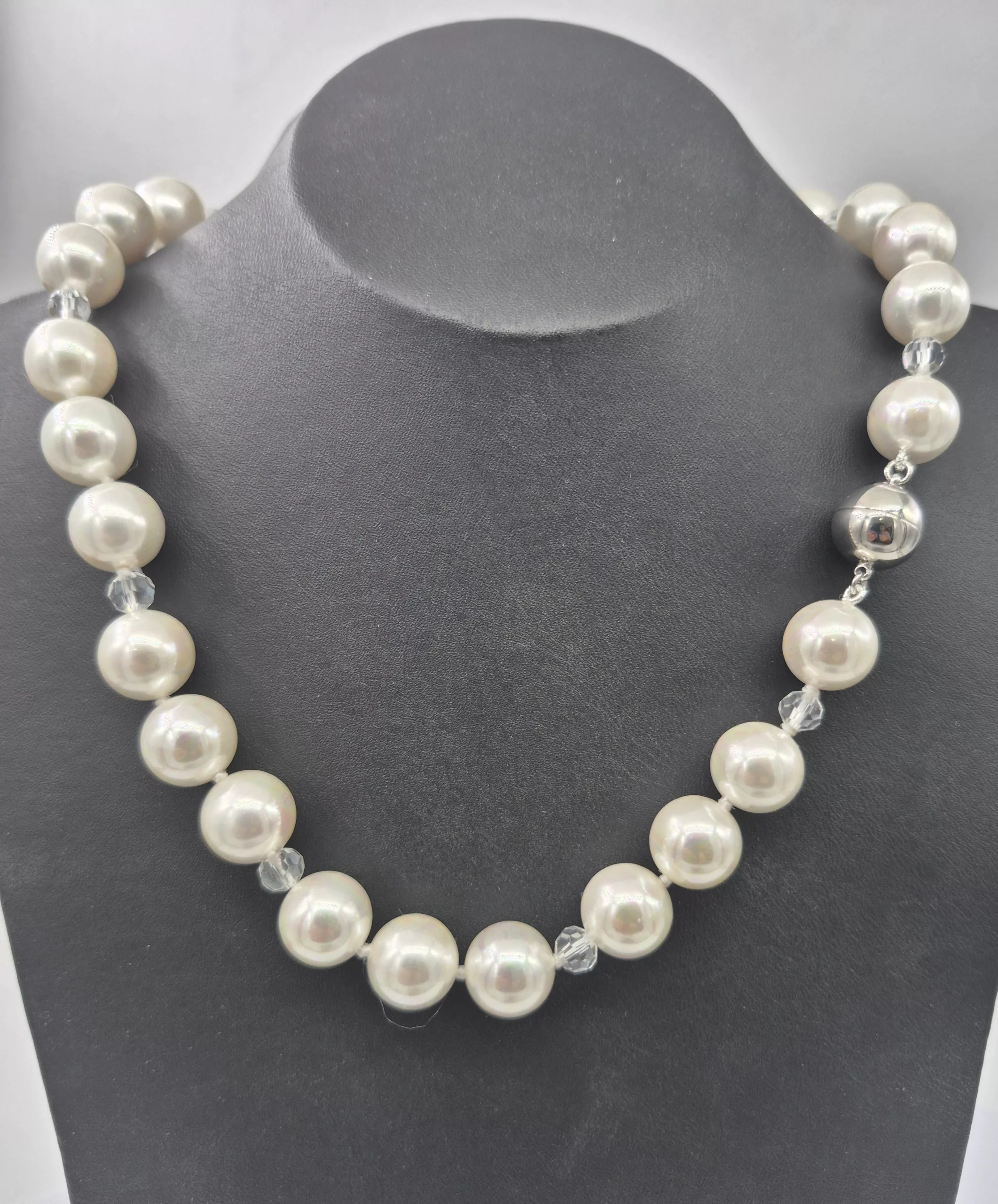 A long gold necklace featuring a large, polished clear quartz gemstone pendant.