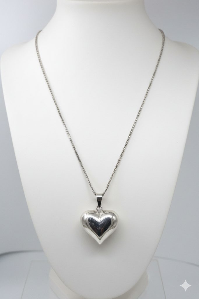 Sterling silver puffed heart pendant on a white Jewellery mannequin.