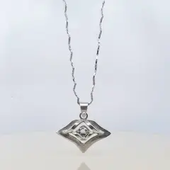 A silver geometric pendant necklace featuring an abstract diamond-shaped design, suspended above a reflective surface against a clean white background.