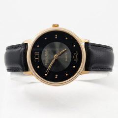 Charles Delon Sophistication men's quartz watch with a round gold-tone case, a minimalist black dial featuring gold stud hour markers and Roman numerals at the 9 o'clock position, paired with a classic black leather strap.