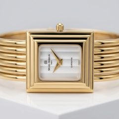 A vintage Michel Herbelin Corynthe ladies' watch featuring a rectangulare gold-plated case and a unique five-strand gold bangle bracelet. The timepiece has a minimalist white vertical-striped dial with gold dauphine hands, presented as a high-quality preloved luxury accessory.
